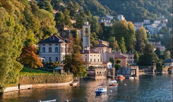 Boats on Lake Como in front of buildings on a green hillside.