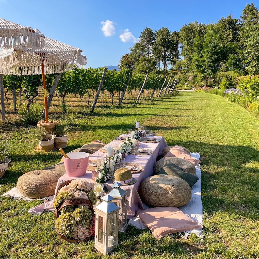 A luxurious picnic spread with sparkling wine and fresh flowers in front of a vineyard