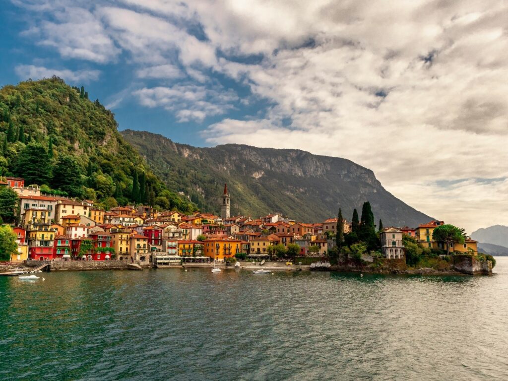 Colorful village on a lake in Italy with mountains in the background.